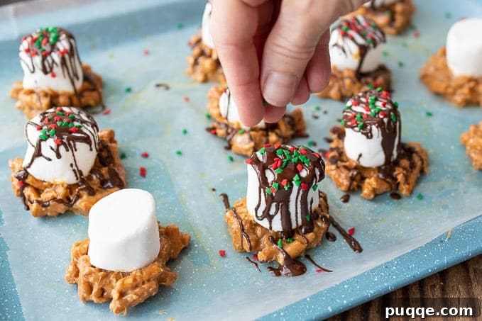 A hand adding colorful sprinkles to a fresh Caramel Marshmallow Treat, adding a festive touch.
