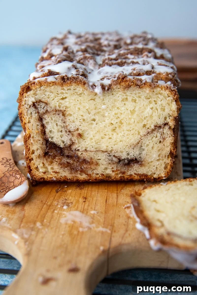 Sweet Cinnamon Gluten-Free Loaf with a Vanilla Drizzle 2 A perfectly baked slice of gluten-free cinnamon bread, adorned with a sweet vanilla glaze, rests on a rustic cutting board, promising a delightful treat.