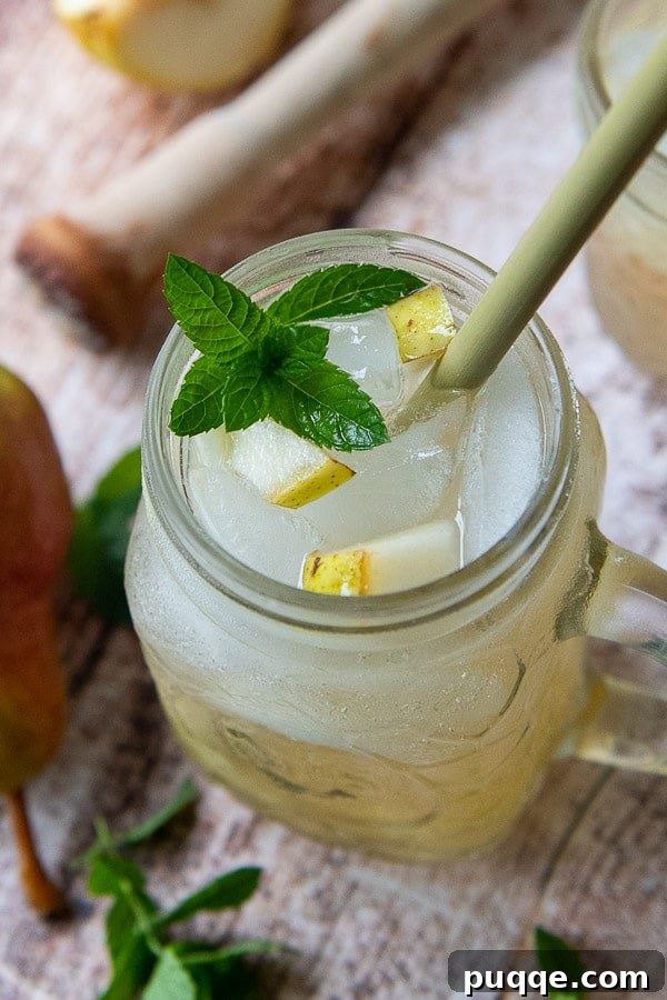 Spiced Pear Elixir 4 A close-up, top-down view of a vibrant Pear Ginger Cocktail, elegantly garnished with a fresh pear slice and a sprig of mint, showcasing its inviting presentation and refreshing qualities.