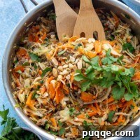 overhead shot of a skillet with egg roll bowl recipe garnished with cilantro and peanuts
