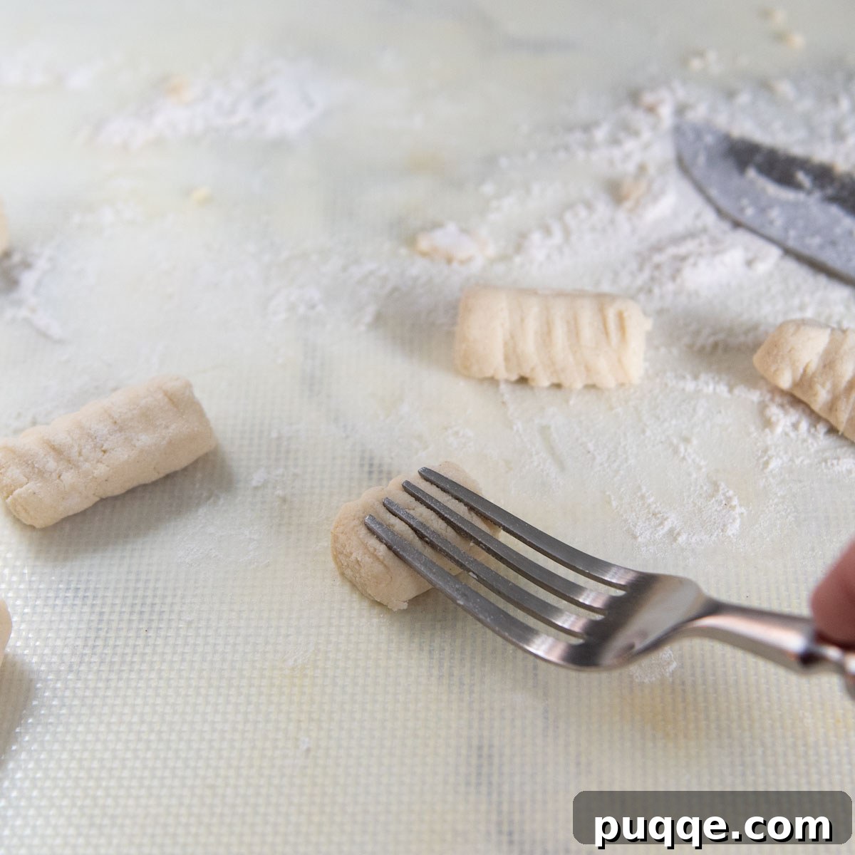 a fork pressing into the dough to make grooves.