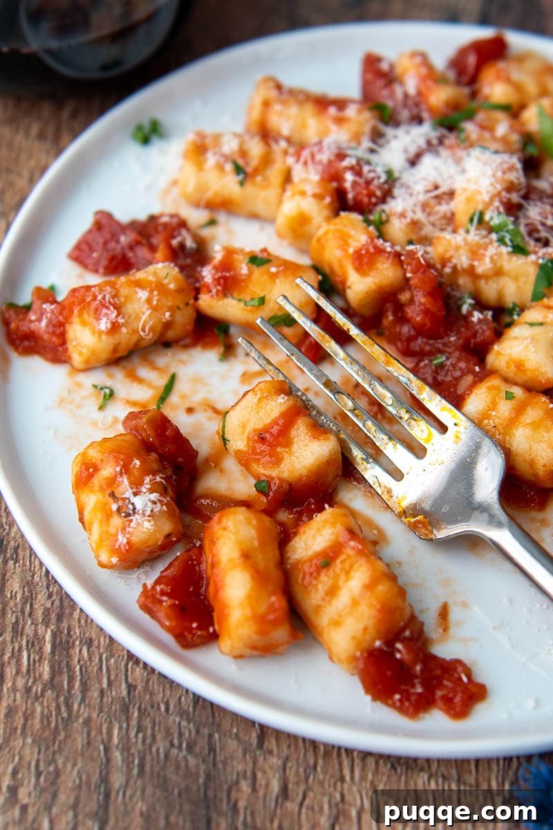 close up of a fork resting on a plate with gnocchi