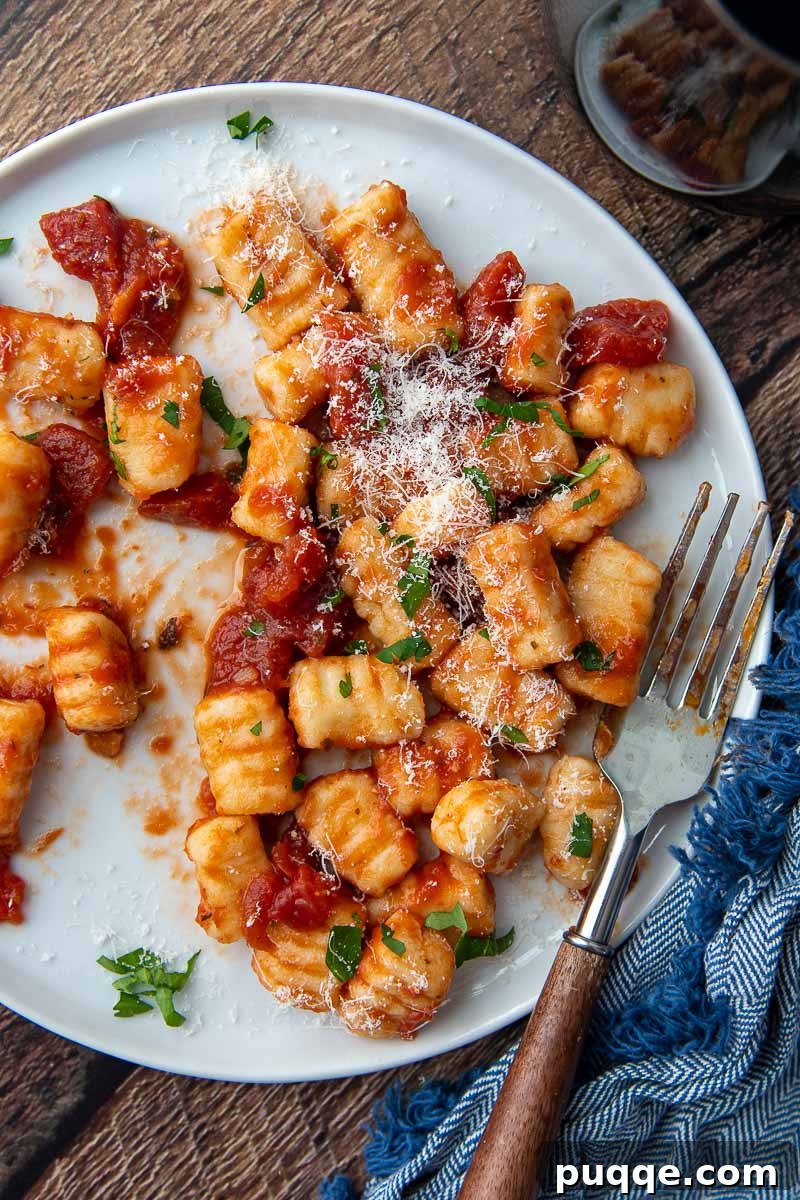 overhead shot of gnocchi on a white plate with a fork resting on it