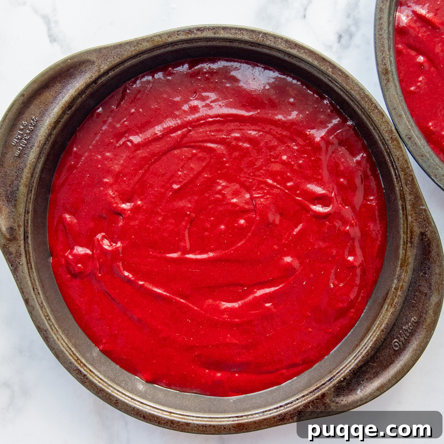 Decadent Gluten Free Red Velvet Pure Moist Perfection 5 The vibrant red cake batter evenly divided and ready for baking in two round cake pans, resting on a countertop.