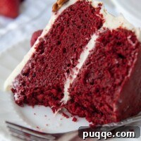 A slice of gluten-free red velvet cake on a white plate with bites taken out, showcasing its moist texture and rich frosting.