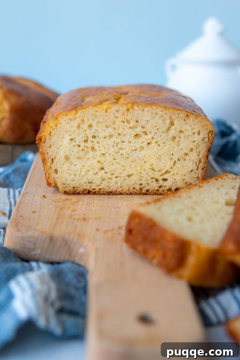 Baking Gluten Free Challah Made Easy 9 A challah bread loaf sliced open on a wooden cutting board, revealing its soft, airy interior.