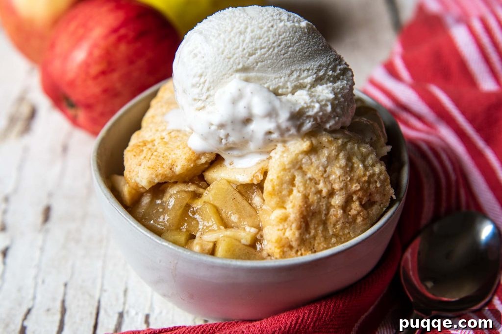 Easy Gluten Free Apple Cobbler with Fluffy Biscuit Topping 9 landscape view of apple cobbler in a white bowl with a spoon resting next to it