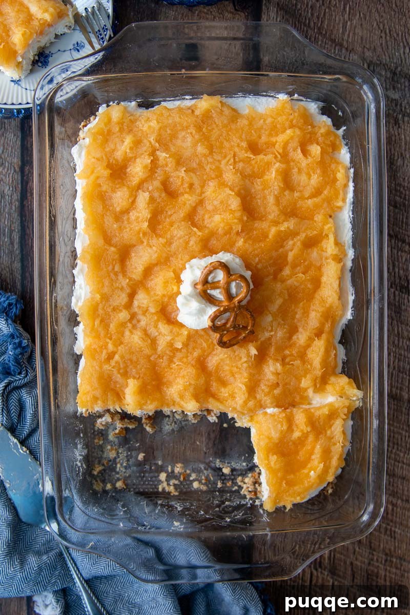 Pineapple Pretzel Delight 5 overhead shot of pineapple pretzel salad in a glass dish with a blue towel next to it