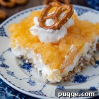 close up of a slice of pretzel salad with pineapple with whipped cream and pretzel on top