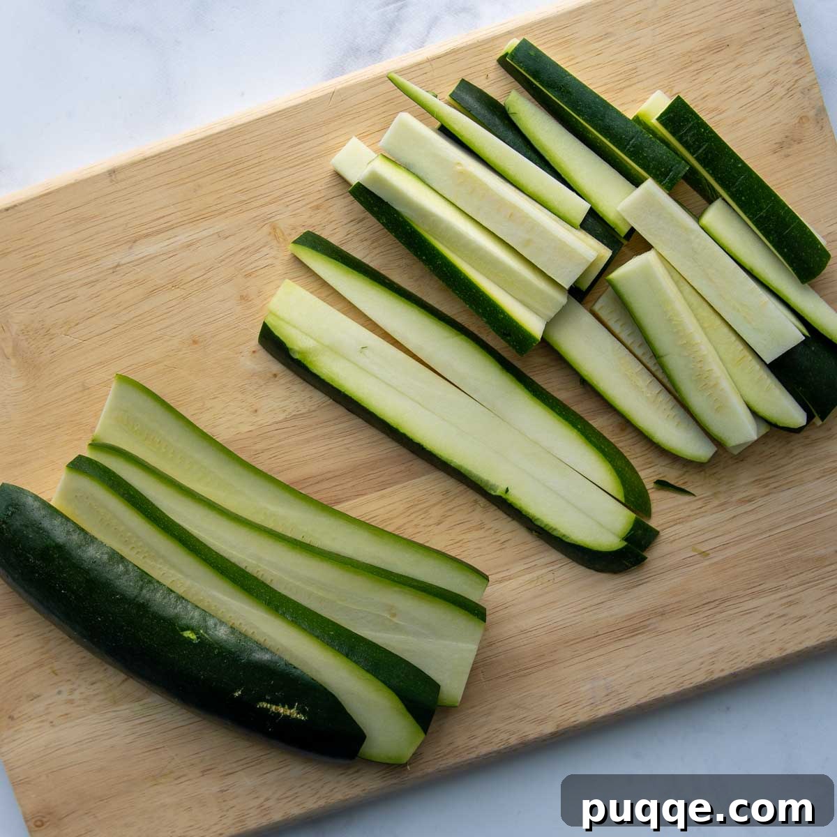 Fresh zucchini expertly cut into uniform sticks, ready for breading.