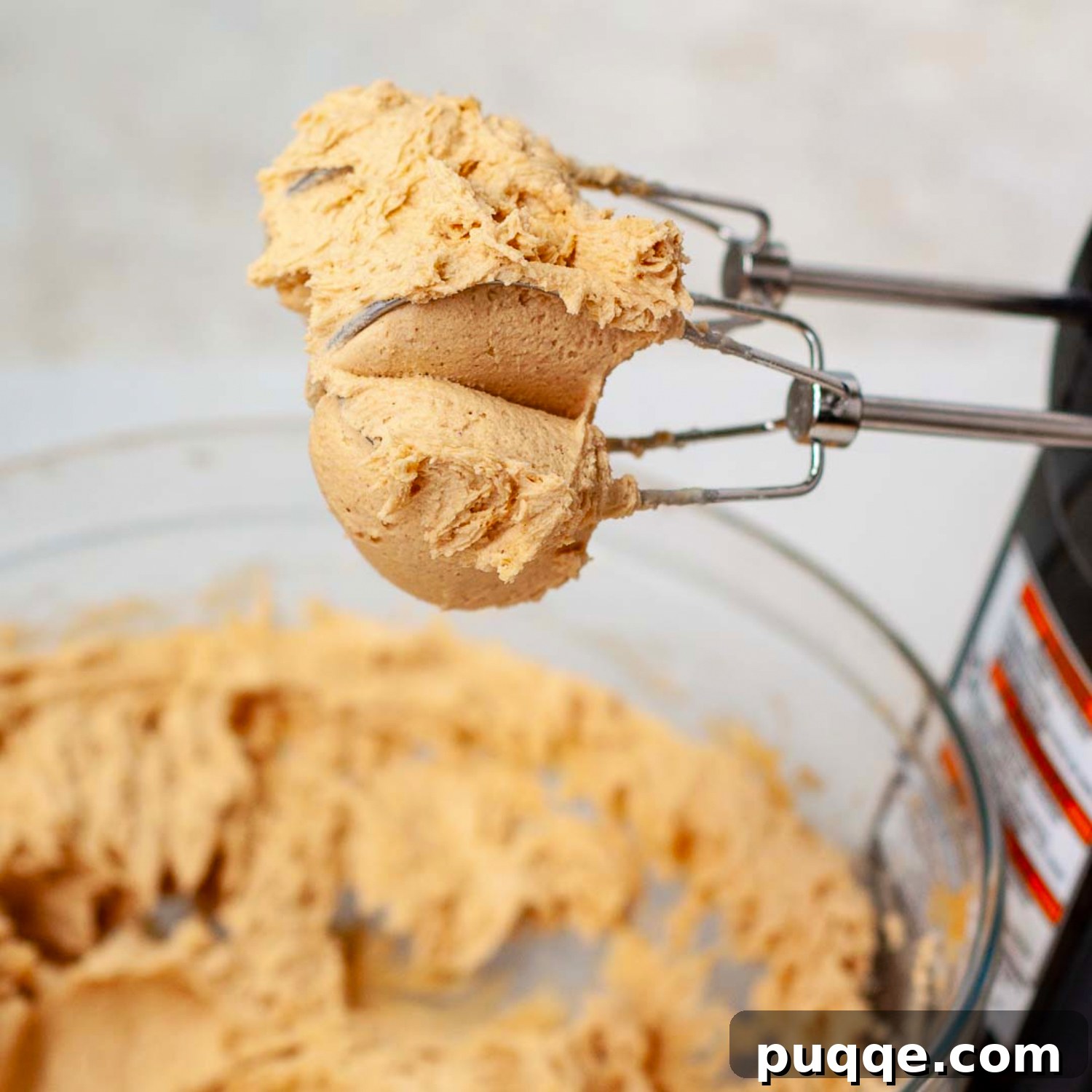 A vibrant peanut butter mixture clinging to a beater, showcasing its thick and creamy texture, ready to be spread as a delicious layer on the brownies.