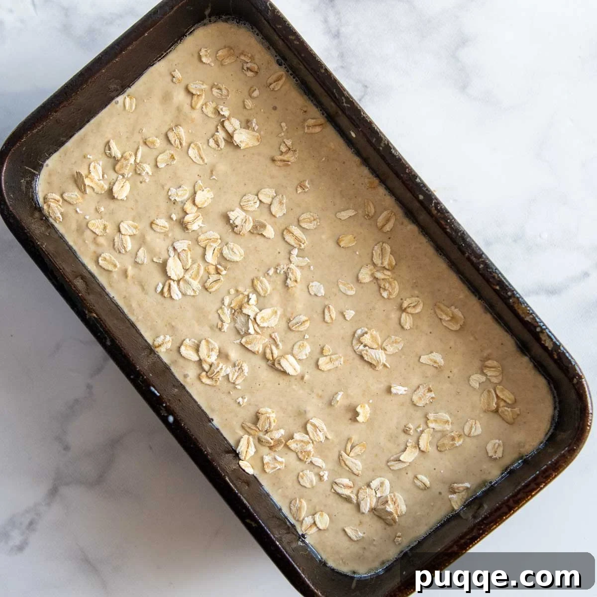 unbaked oat flour bread batter in a loaf pan, ready for the oven