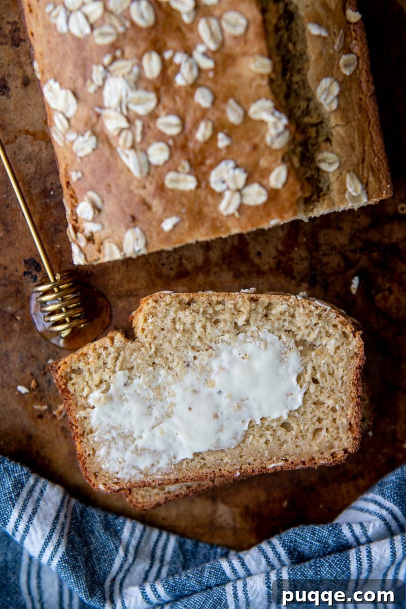 a slice of gluten free oatmeal bread face up with butter on it, ready to be enjoyed