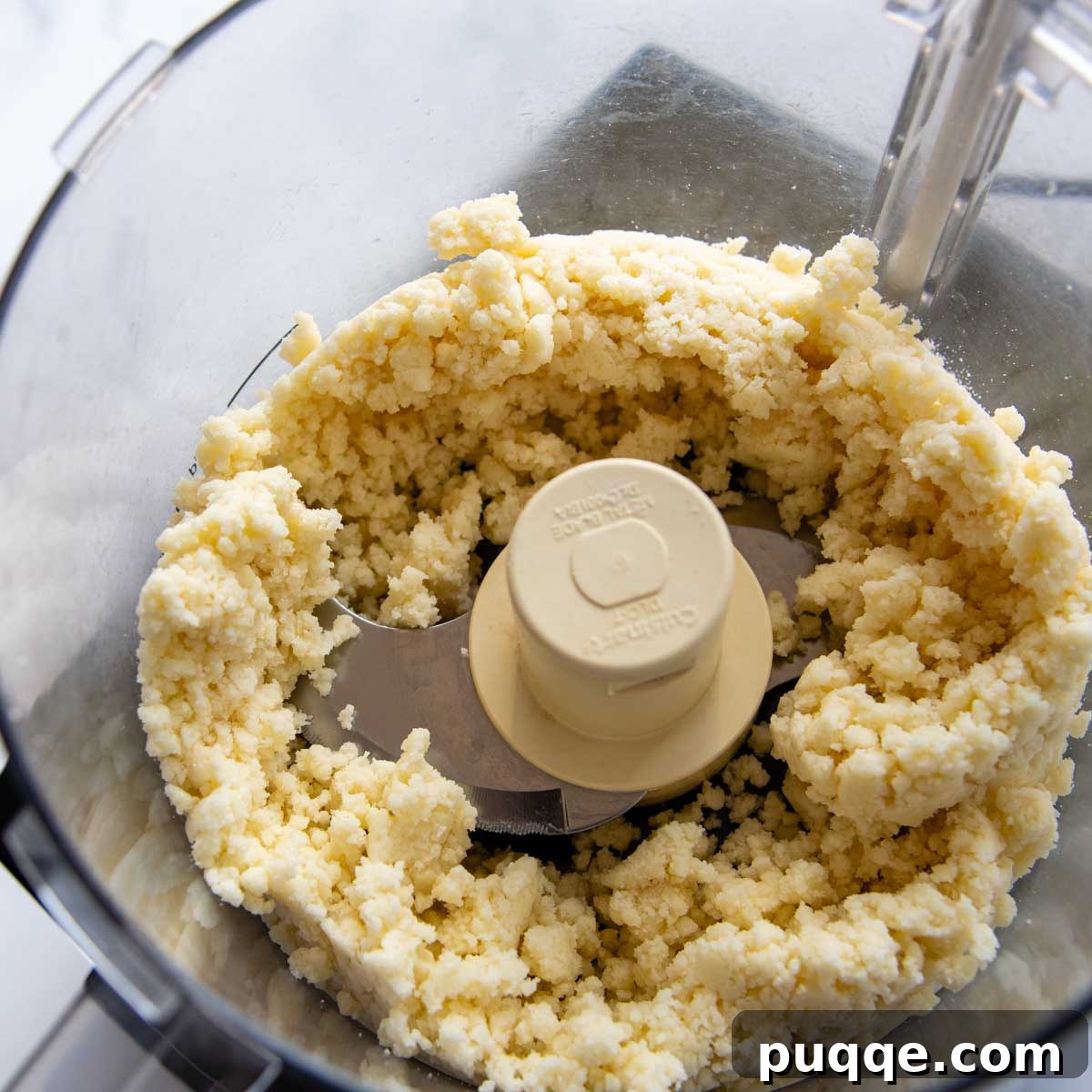The gluten-free shortbread crust ingredients being blended in a food processor, appearing as fine crumbs.