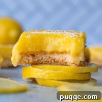 A gluten-free lemon bar with a bite taken out sitting on top of sliced lemons