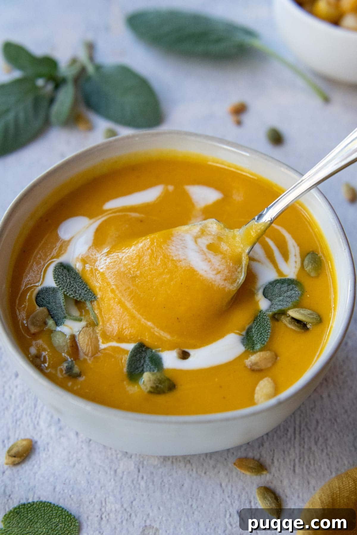 The Ultimate Panera Style Butternut Squash Soup Homemade Perfection 7 a spoon lifting out a bite of soup from a white bowl