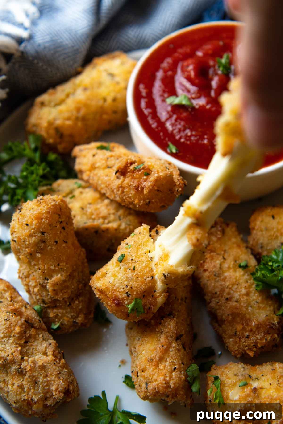 Wallet-Friendly Gluten-Free Meals: 40+ Easy Ideas 24 A hand gently pulling apart crispy gluten-free mozzarella sticks, showing the irresistible melted cheese stretching.