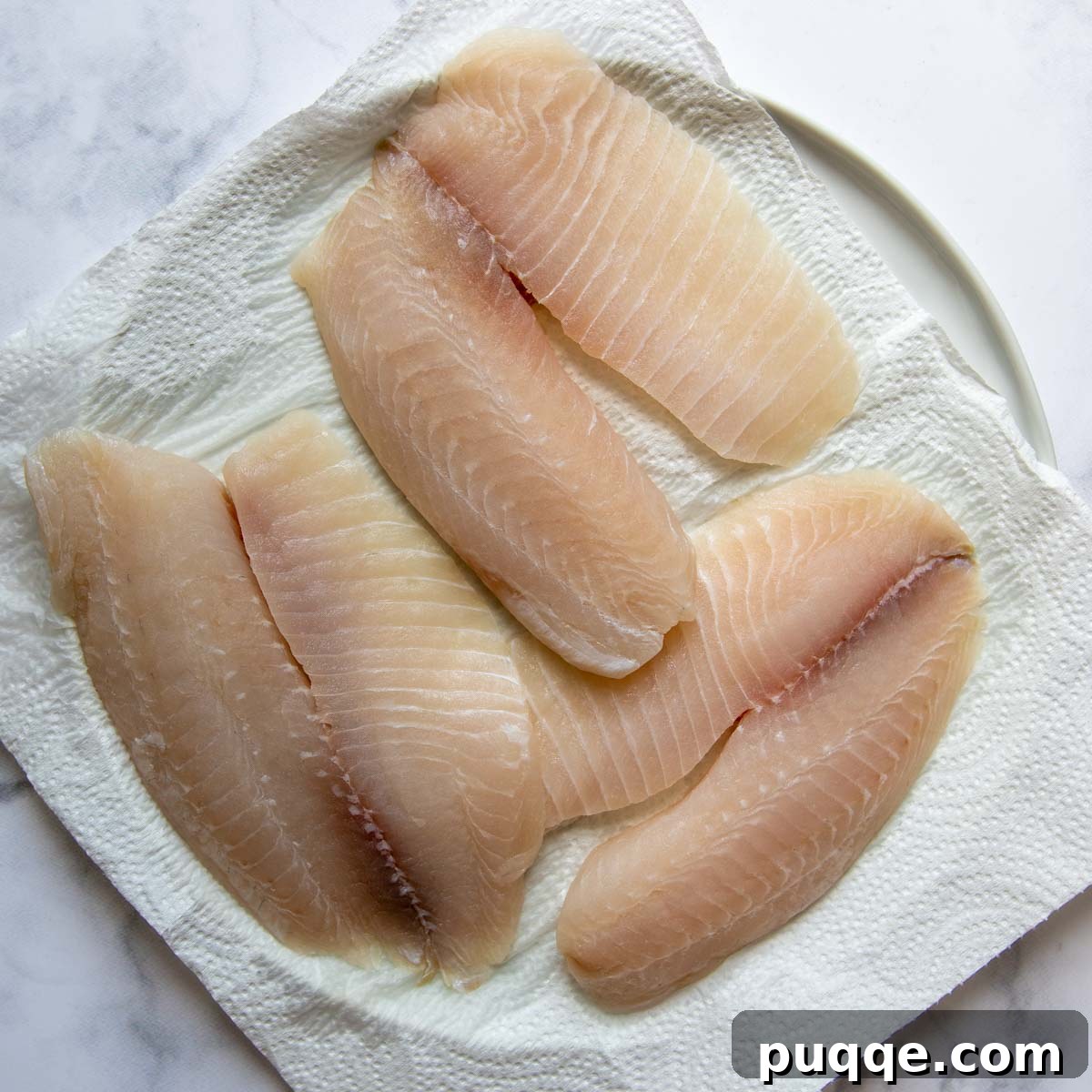 Flavorful Gluten Free Blackened Fish Tacos Ready in 30 3 Fish being patted dry on paper towels to ensure crispy baking.