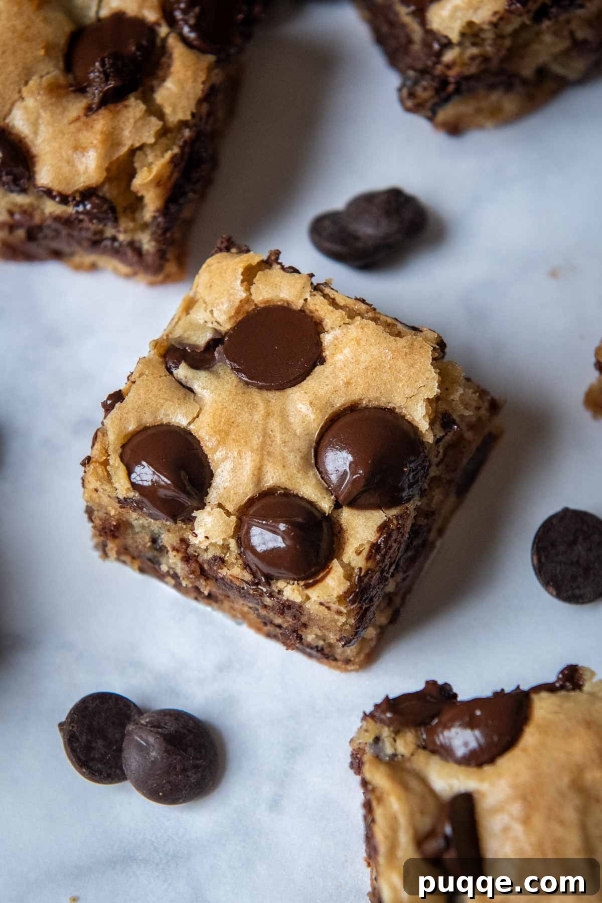 A close-up view of the top of a freshly baked gluten-free blondie, featuring melting chocolate chips and a golden, crinkled surface.