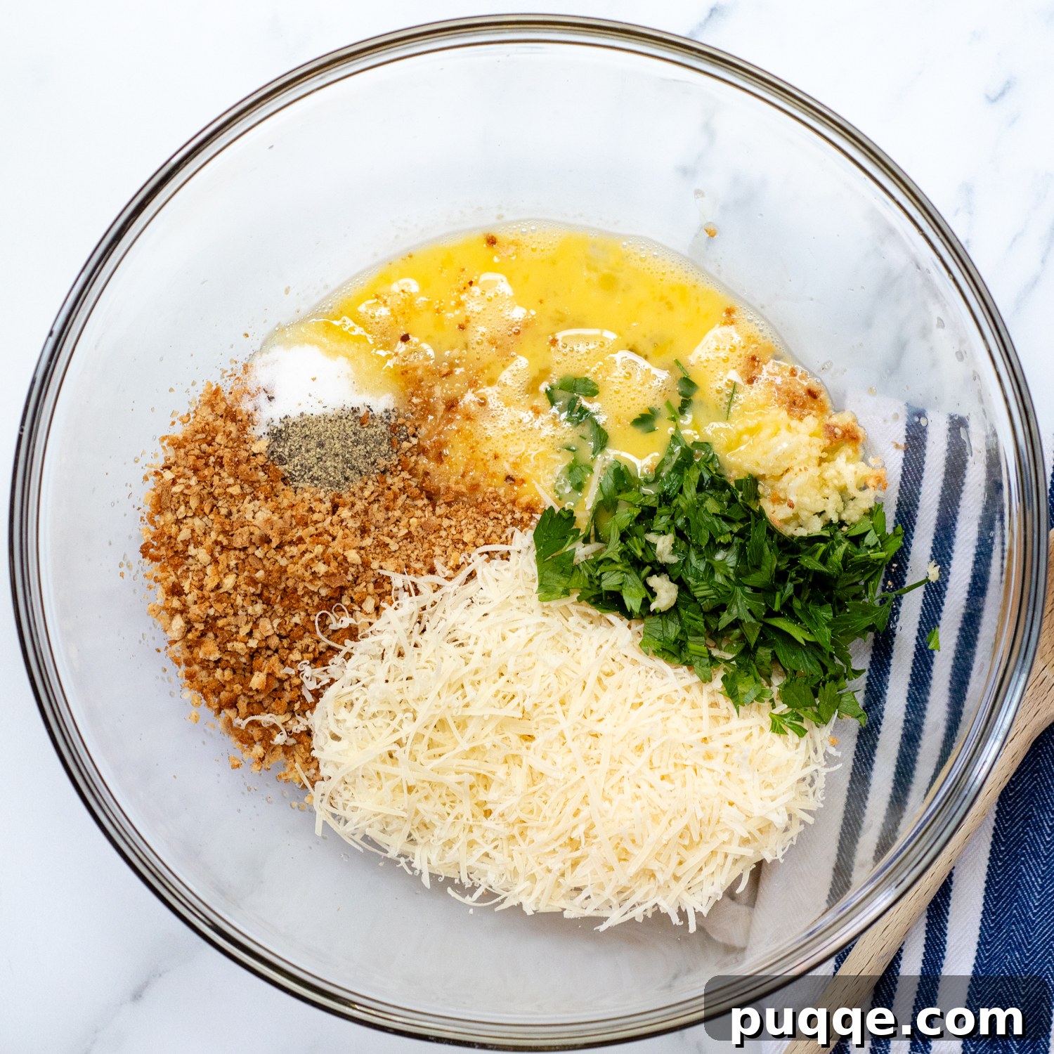 bread crumbs, cheese, parsley, and eggs in a glass bowl.