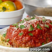 a large white serving dish with Italian meatloaf served on a bed of spaghetti