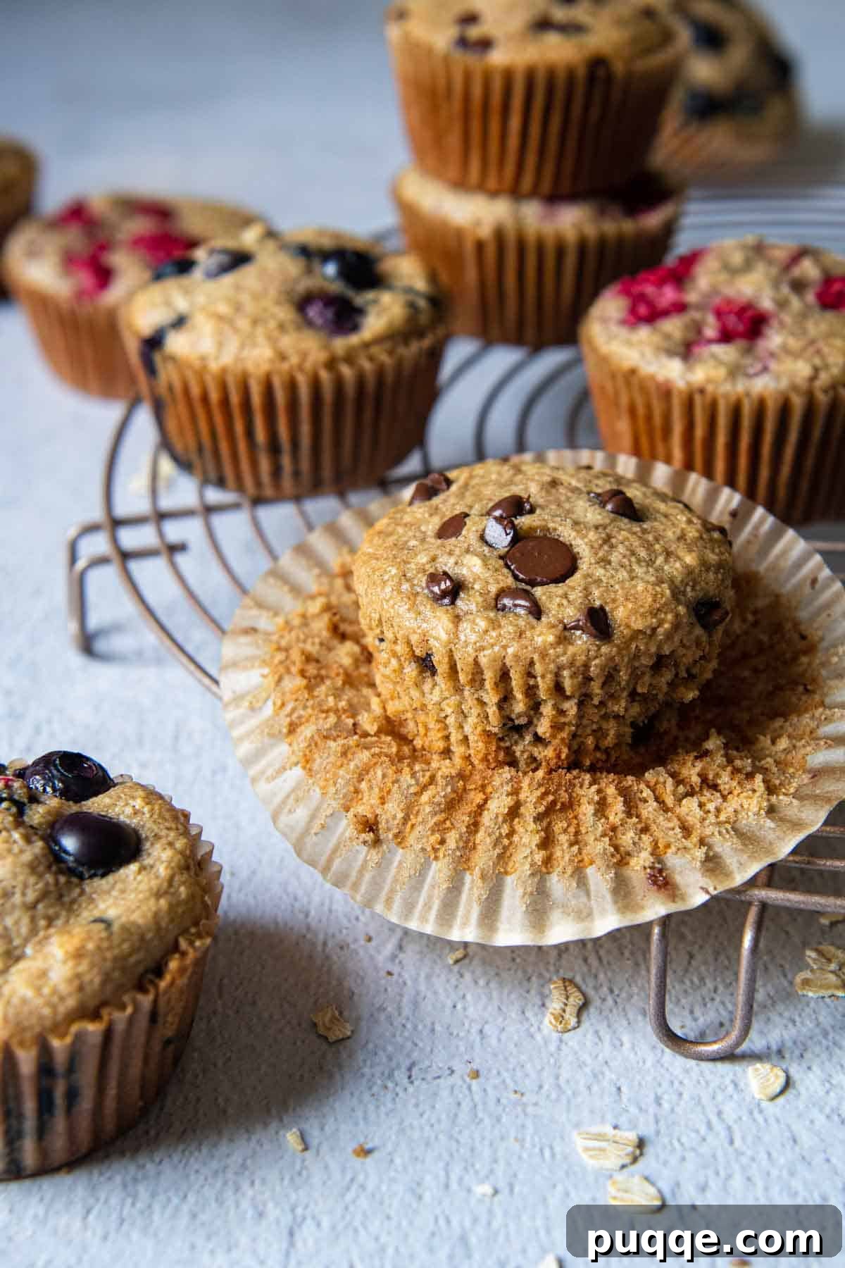 Pillowy 5-Minute Gluten-Free Oat Muffins 7 A mouth-watering assortment of oatmeal muffins, featuring chocolate chip, blueberry, and plain varieties, arranged beautifully on a rustic wooden surface.