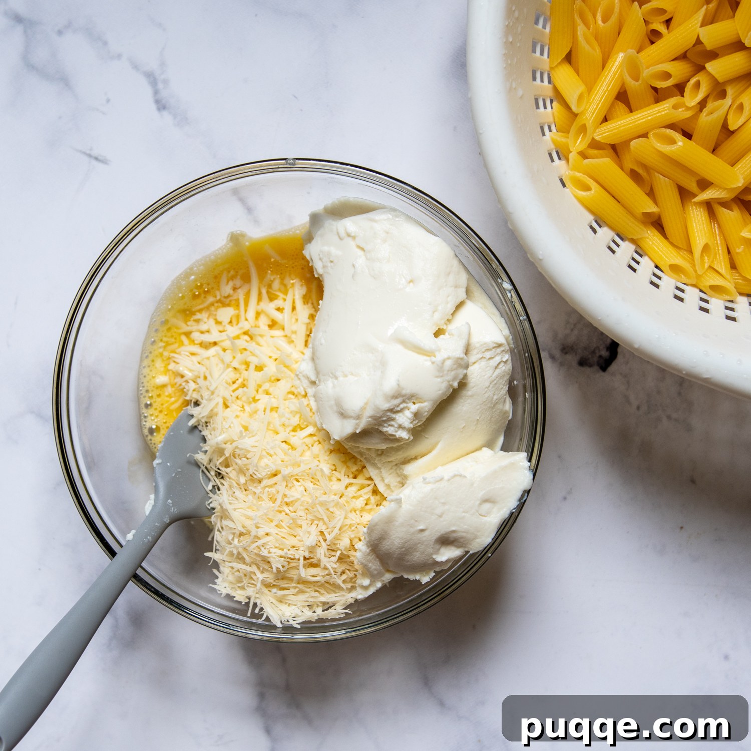 The creamy ricotta filling in a bowl next to a pot of cooked ziti pasta, ready for assembly.