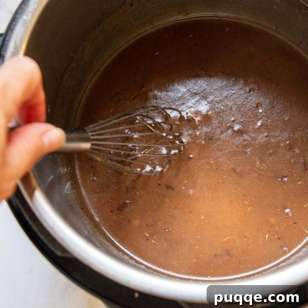Fall-Apart Tender Instant Pot Pork 4 A close-up image showing the tangy gravy being expertly whisked to a perfect consistency directly in the Instant Pot after the pork has cooked.