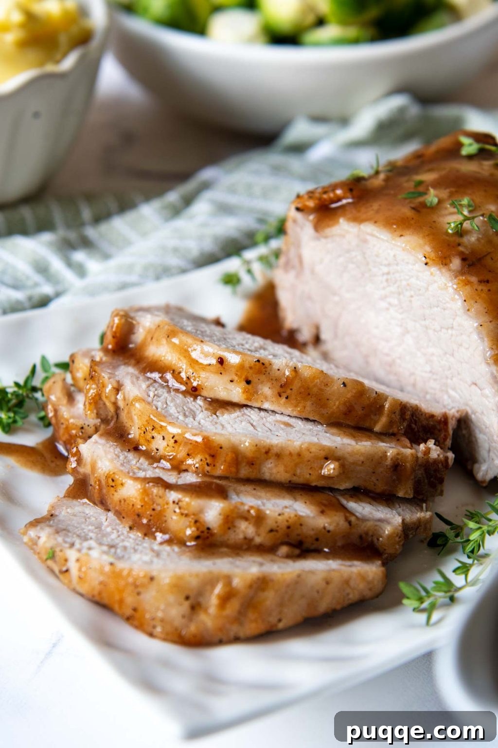 Fall-Apart Tender Instant Pot Pork 6 A close-up view of succulent slices of Instant Pot pork roast, showcasing its juicy texture and rich, golden-brown crust on a white platter.