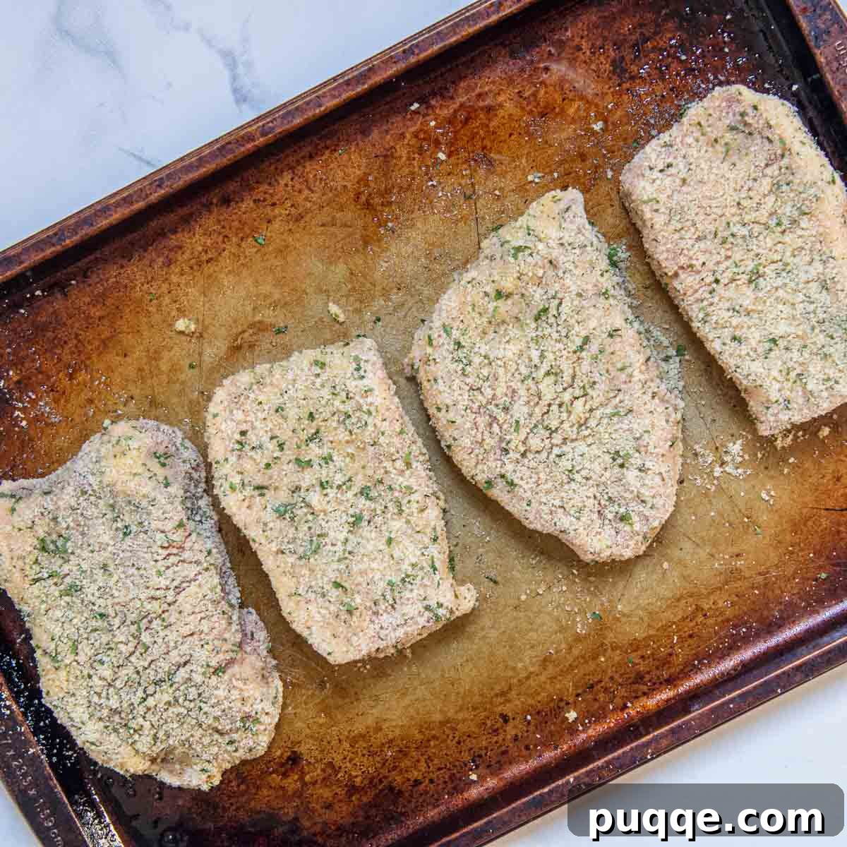 Crispy Almond Crusted Baked Pork Chops Gluten Free 4 Unbaked, breaded pork chops arranged neatly on a baking sheet, ready for oven-frying.
