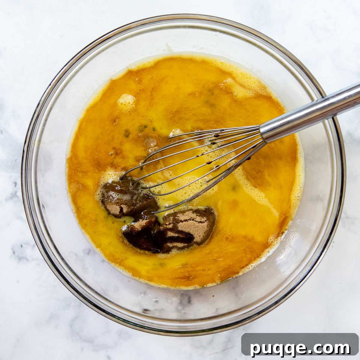 pie filling ingredients being whisked in a large glass bowl.