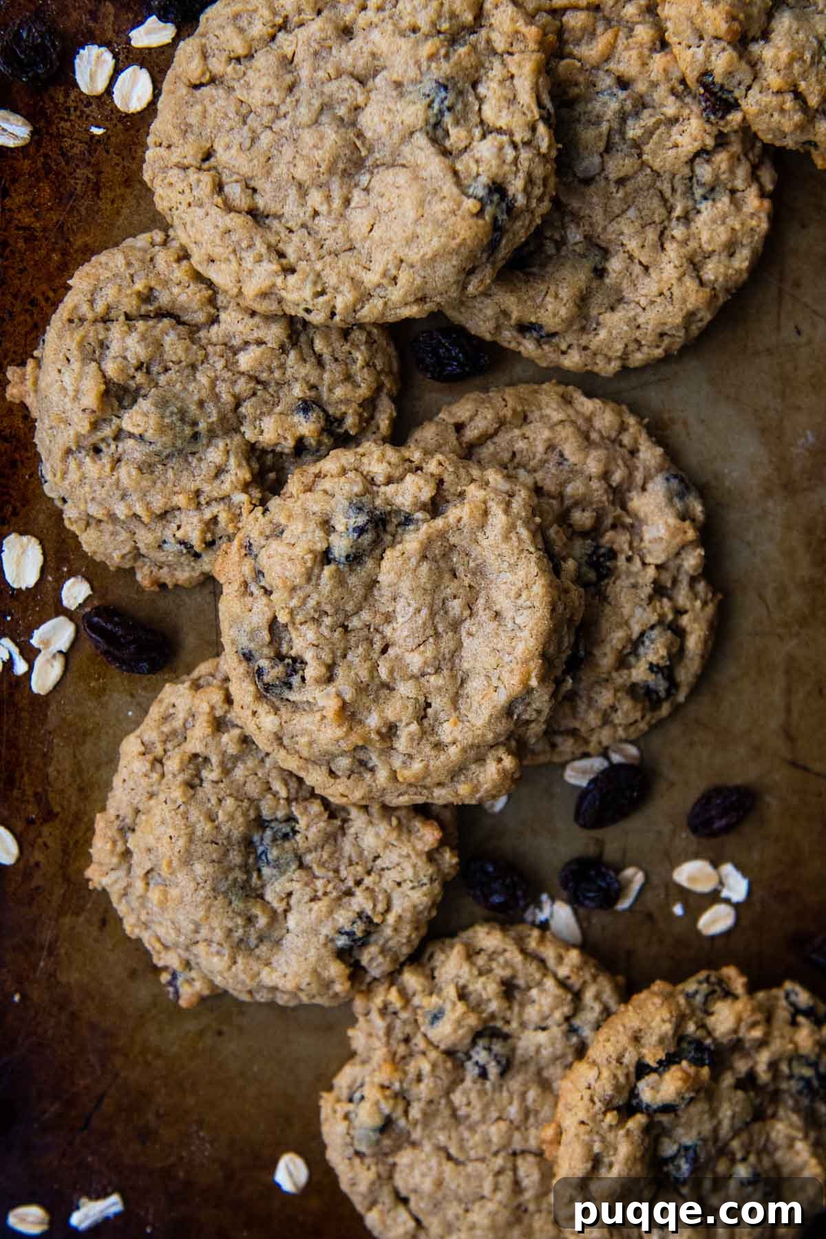 15 Minute Gluten Free Flourless Oatmeal Raisin Cookies 6 A stack of golden-brown gluten-free oatmeal cookies artfully arranged on a rustic baking sheet, ready to be enjoyed.