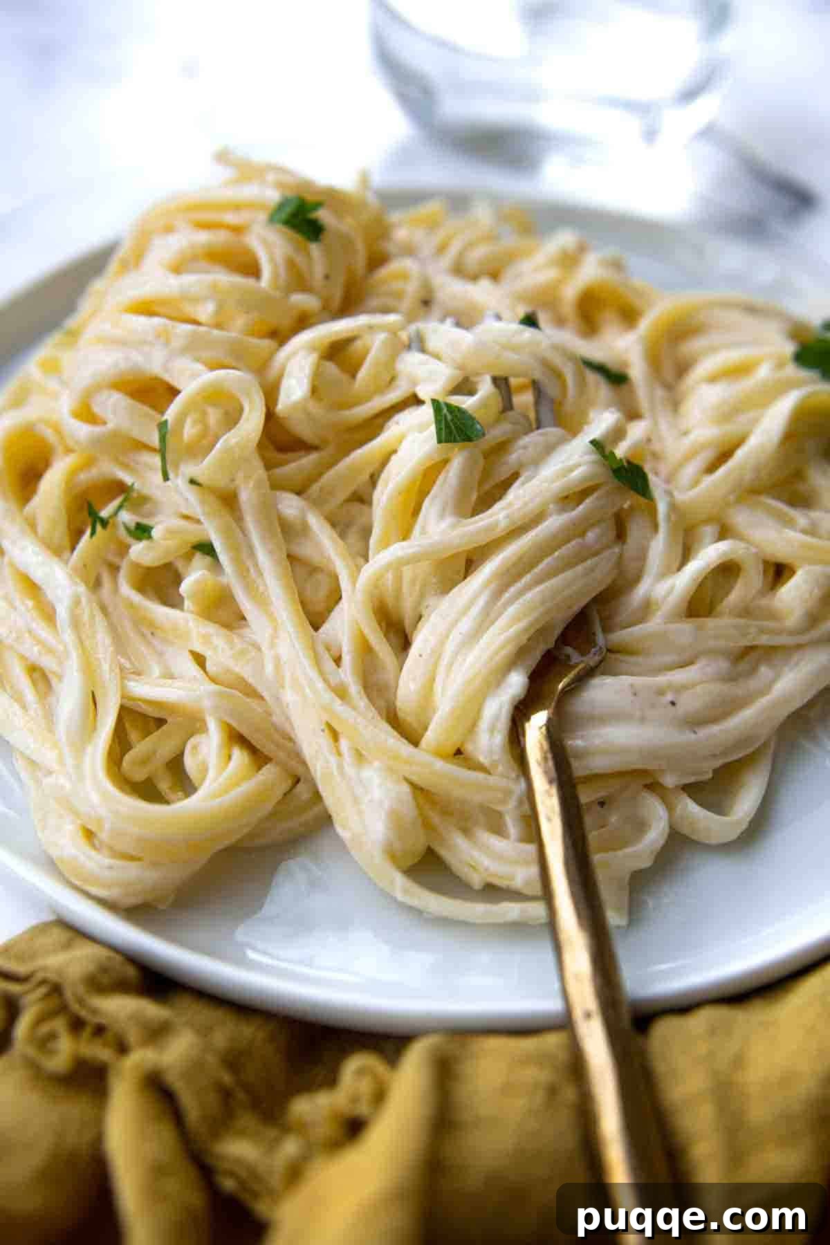 Quick and Creamy Gluten-Free Alfredo in 10 Minutes 2 A fork wrapped around a generous serving of perfectly creamy gluten-free fettuccine alfredo, garnished with fresh parsley.