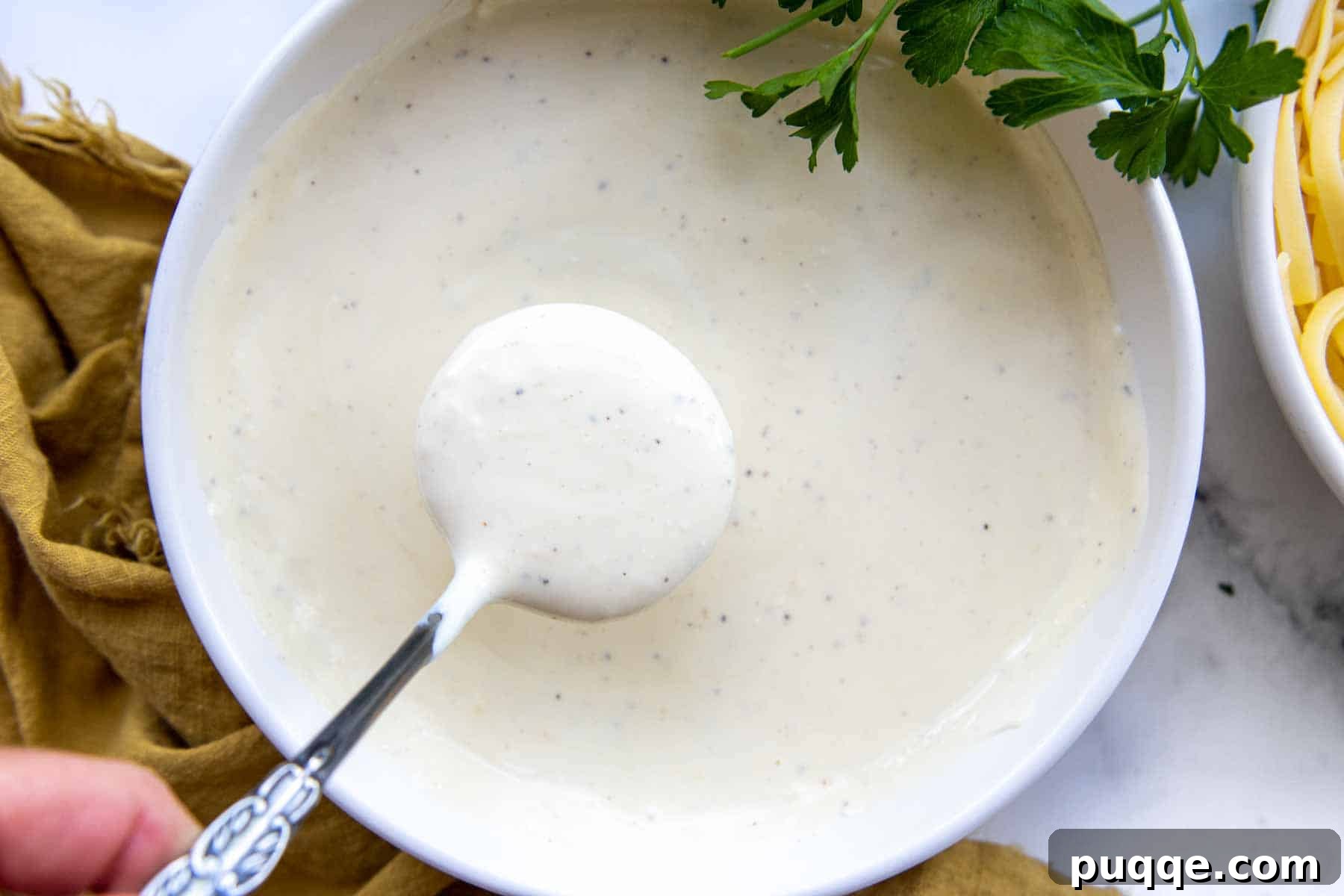 Quick and Creamy Gluten-Free Alfredo in 10 Minutes 5 A ladle holding a generous scoop of thick, creamy gluten-free alfredo sauce, showcasing its perfect texture.