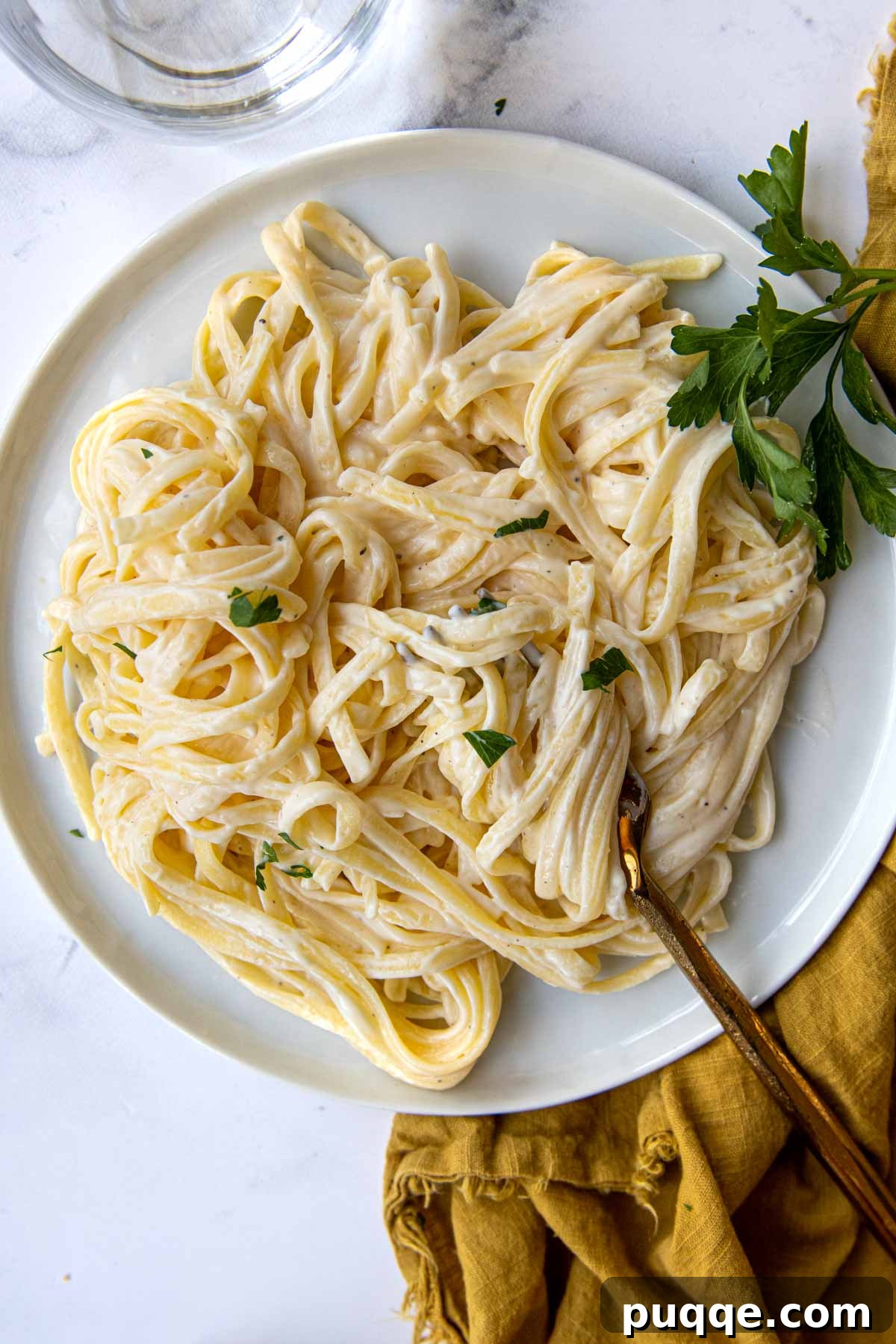 Quick and Creamy Gluten-Free Alfredo in 10 Minutes 6 An overhead shot of a plate of creamy gluten-free fettuccine alfredo with a fork resting on the side, ready to be enjoyed.