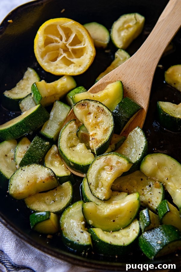 close up shot of cooked zucchini being held by a wooden spoon