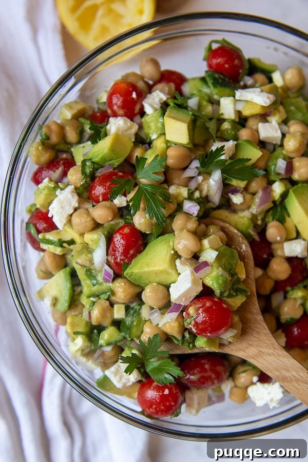 a wooden spoon holding up a serving of chickpea avocado salad
