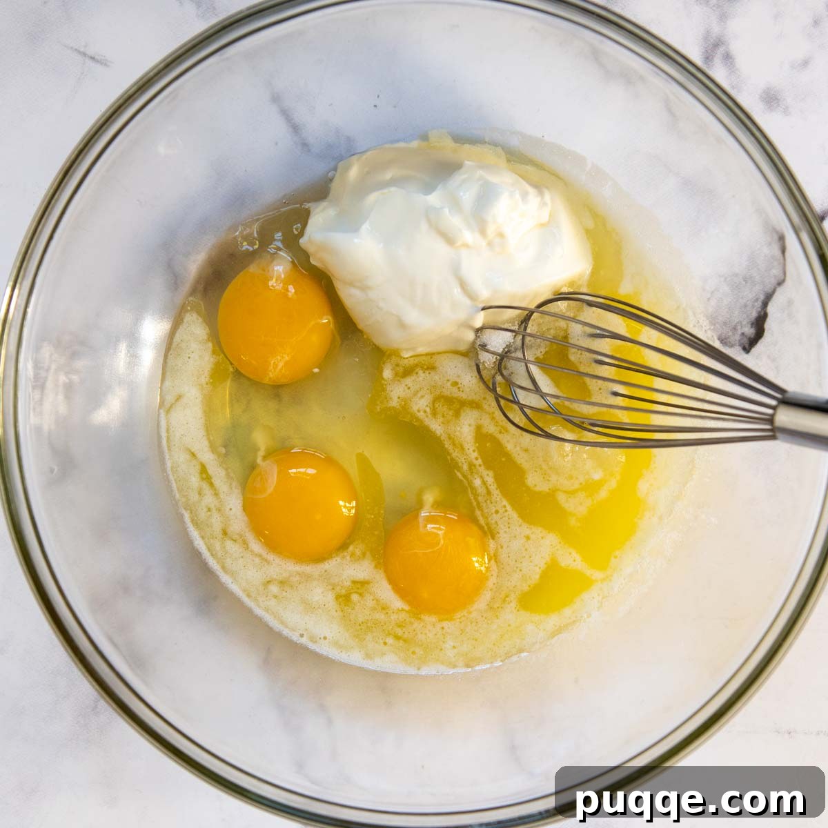 Creamy Fluffy Gluten Free Corn Casserole Made Simple 3 Wet ingredients for corn pudding, including eggs, sour cream, sugar, and melted butter, whisked together in a large bowl.