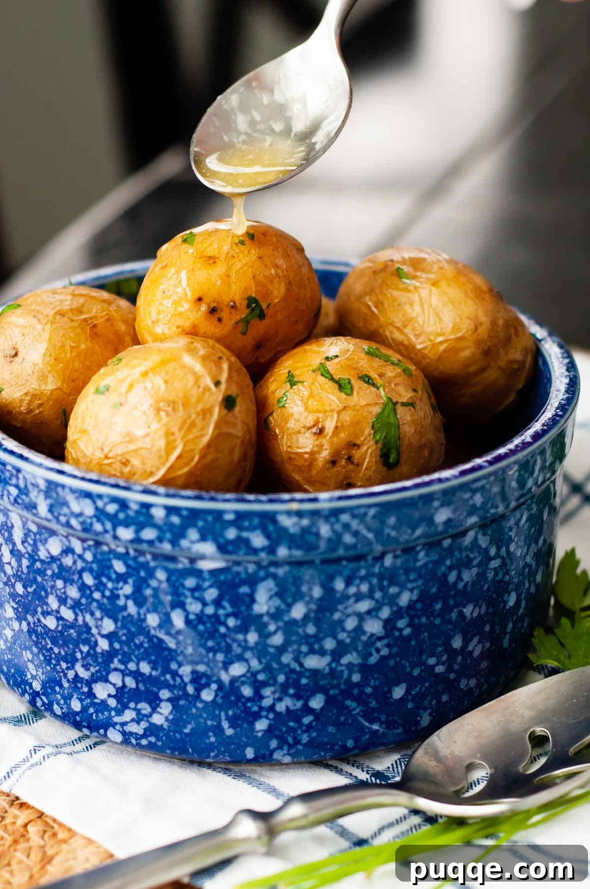 A generous spoonful of rich, melted butter being drizzled over a bowl of Syracuse-Style Salt Potatoes, highlighting their incredibly creamy texture and inviting appearance.
