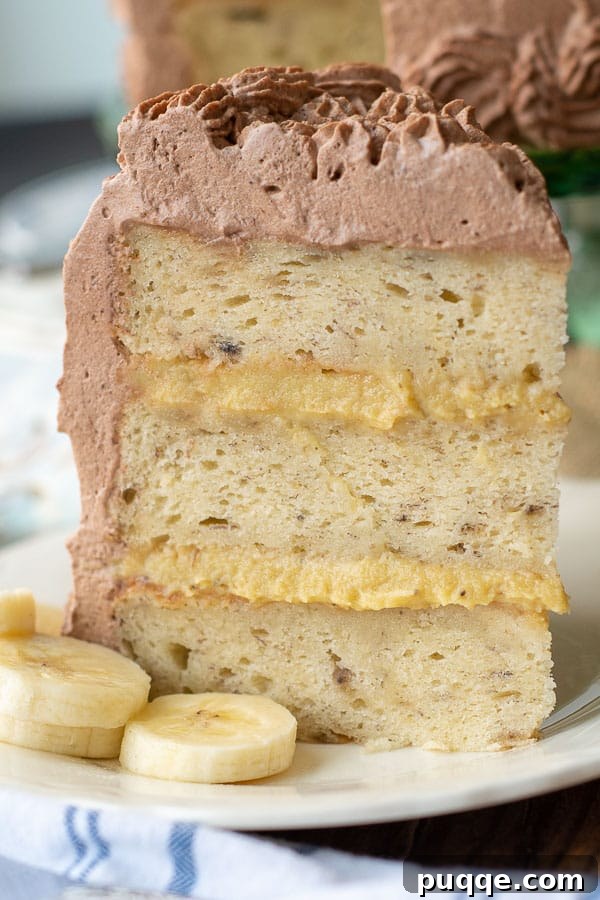 A delightful slice of fluffy banana cake with a creamy banana filling stands tall on a plate, promising a light and flavorful dessert experience.