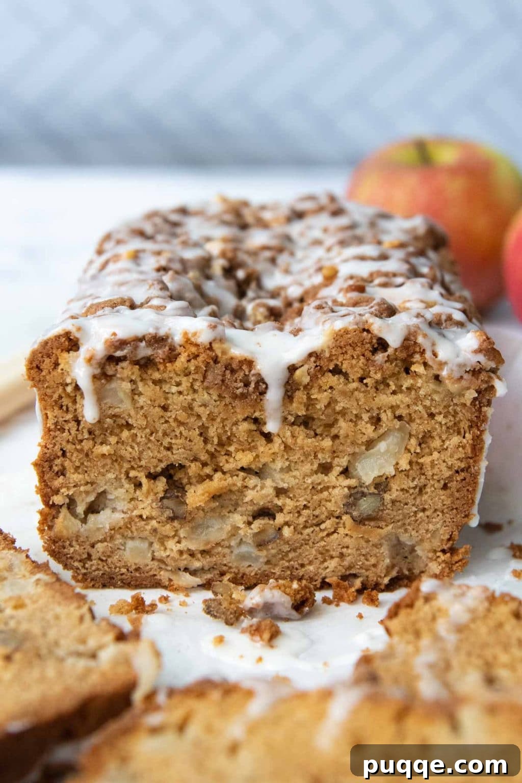Cozy Gluten-Free Apple Cinnamon Crumble Bread 8 a single slice of gluten free apple bread with vanilla glaze, positioned next to a whole loaf and fresh apples