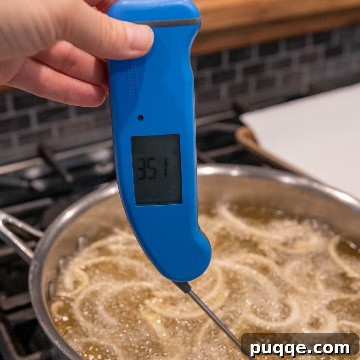 An instant-read thermometer accurately measuring the oil temperature in a deep skillet during frying.