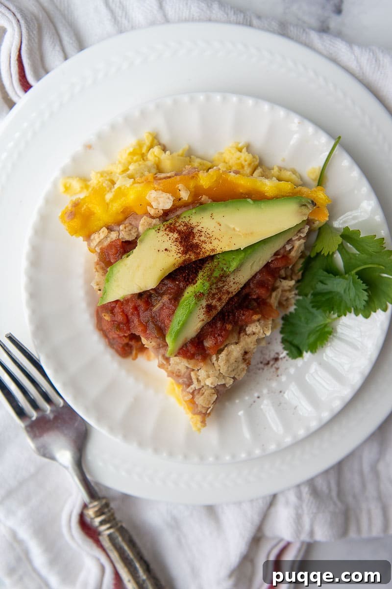 a slice of frittata on a white plate with sliced avocados on top