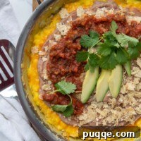 overhead shot of mexican frittata in a skillet layered with beans, chips, and salsa