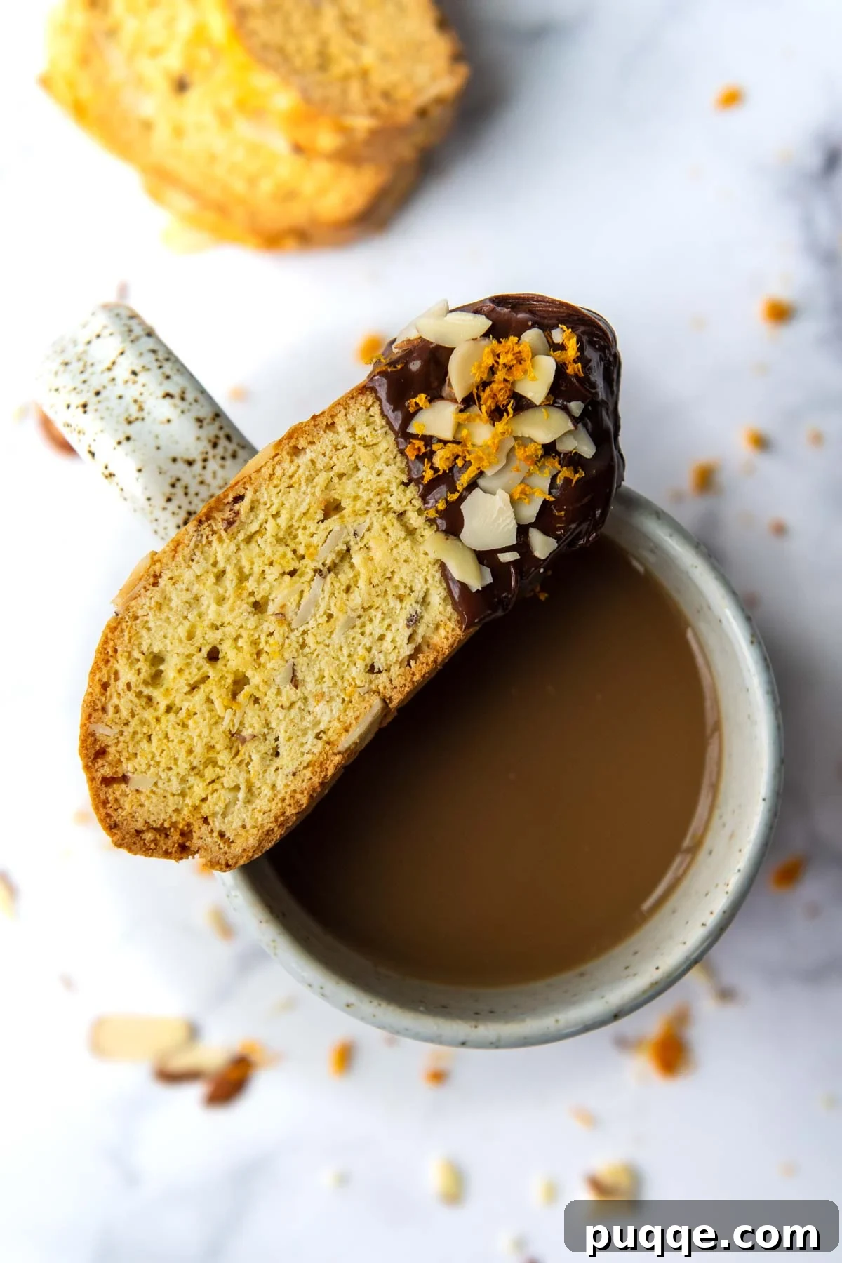 Feather-Light, Perfectly Crispy Gluten-Free Biscotti 2 A perfectly baked gluten-free biscotti, partially dipped in rich dark chocolate, artfully balanced on the rim of a steaming coffee cup, inviting a moment of blissful indulgence.