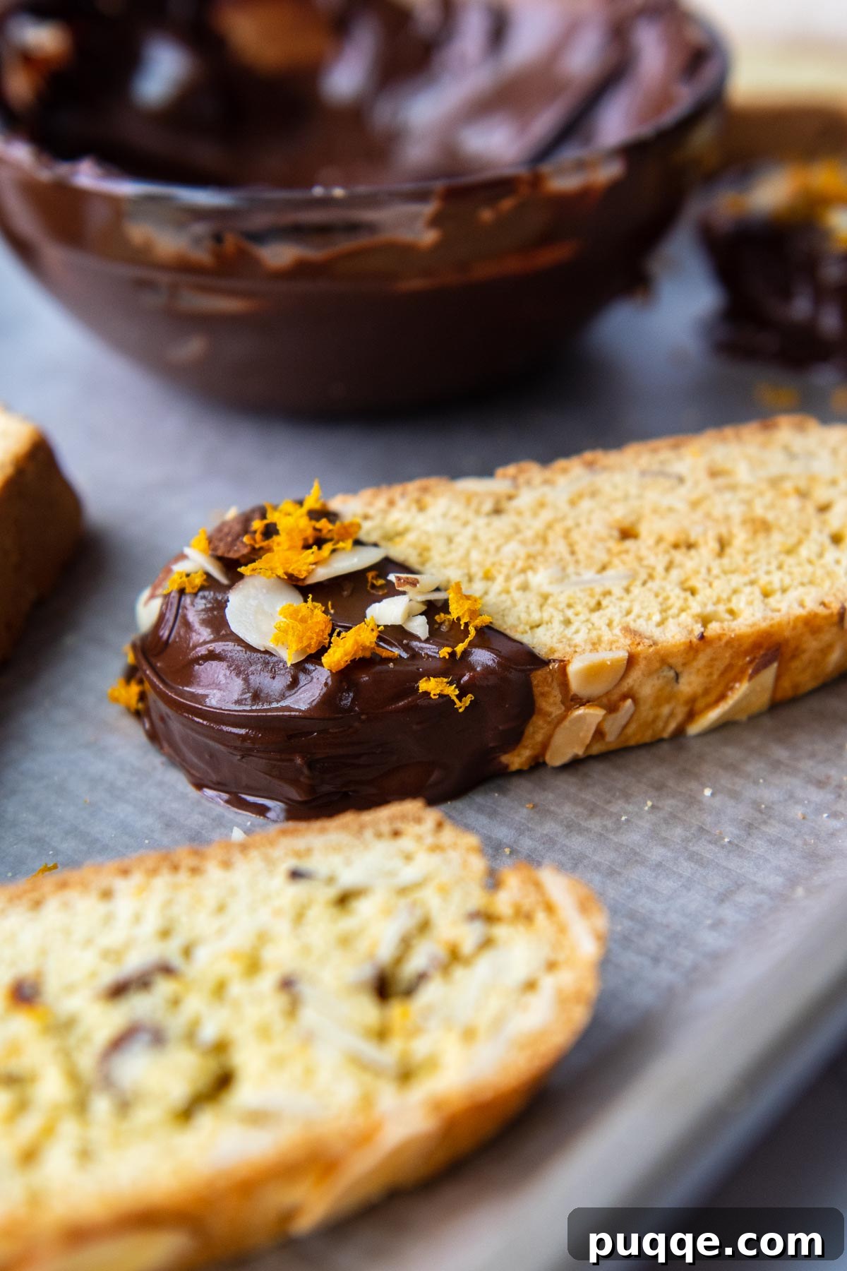 Feather-Light, Perfectly Crispy Gluten-Free Biscotti 8 A close-up photograph highlighting the chocolate-dipped tip of a perfectly golden-brown biscotti, resting invitingly on a baking sheet, ready to be enjoyed.