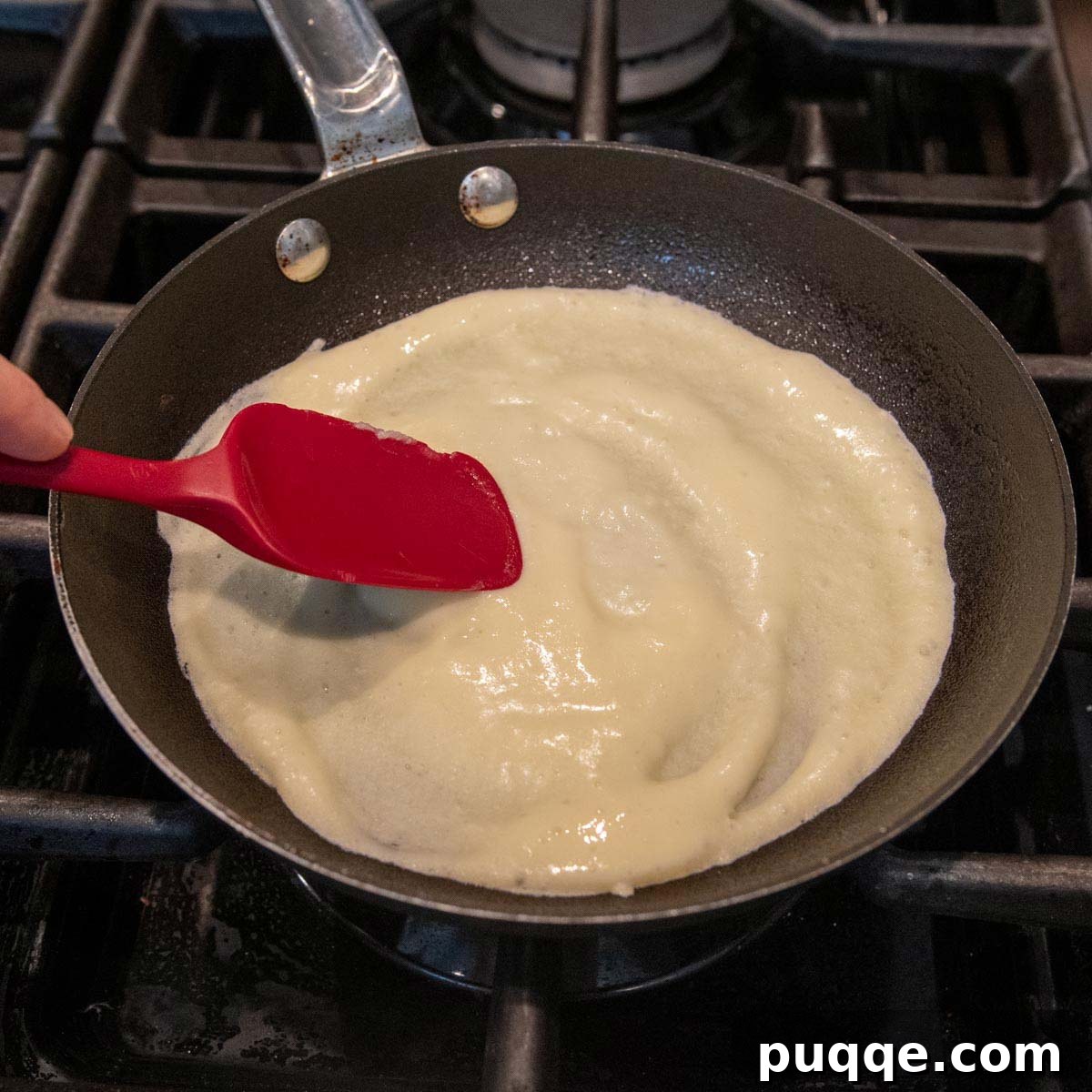 crepe batter in a skillet being spread out.