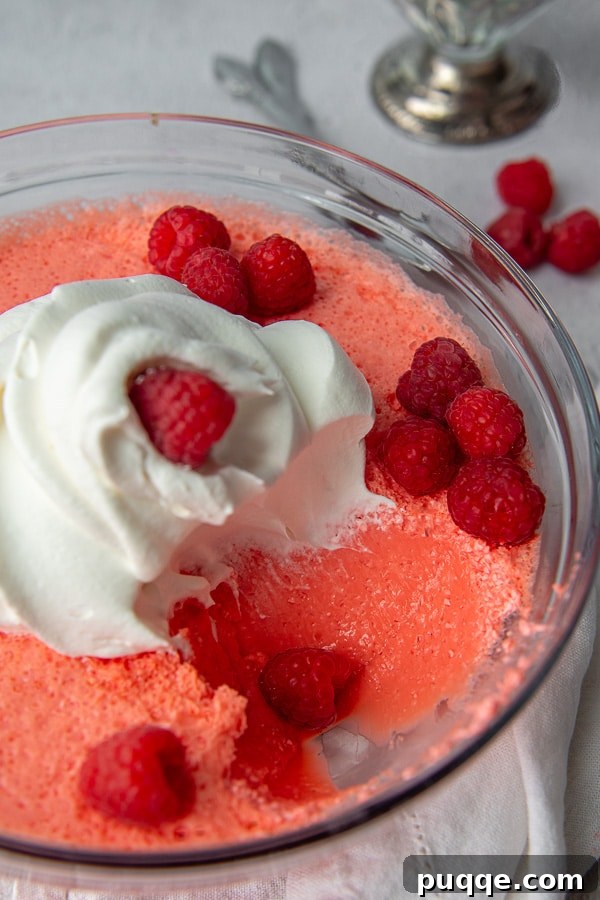 A scoop of vibrant jello salad taken out of a serving bowl, showcasing its creamy texture.