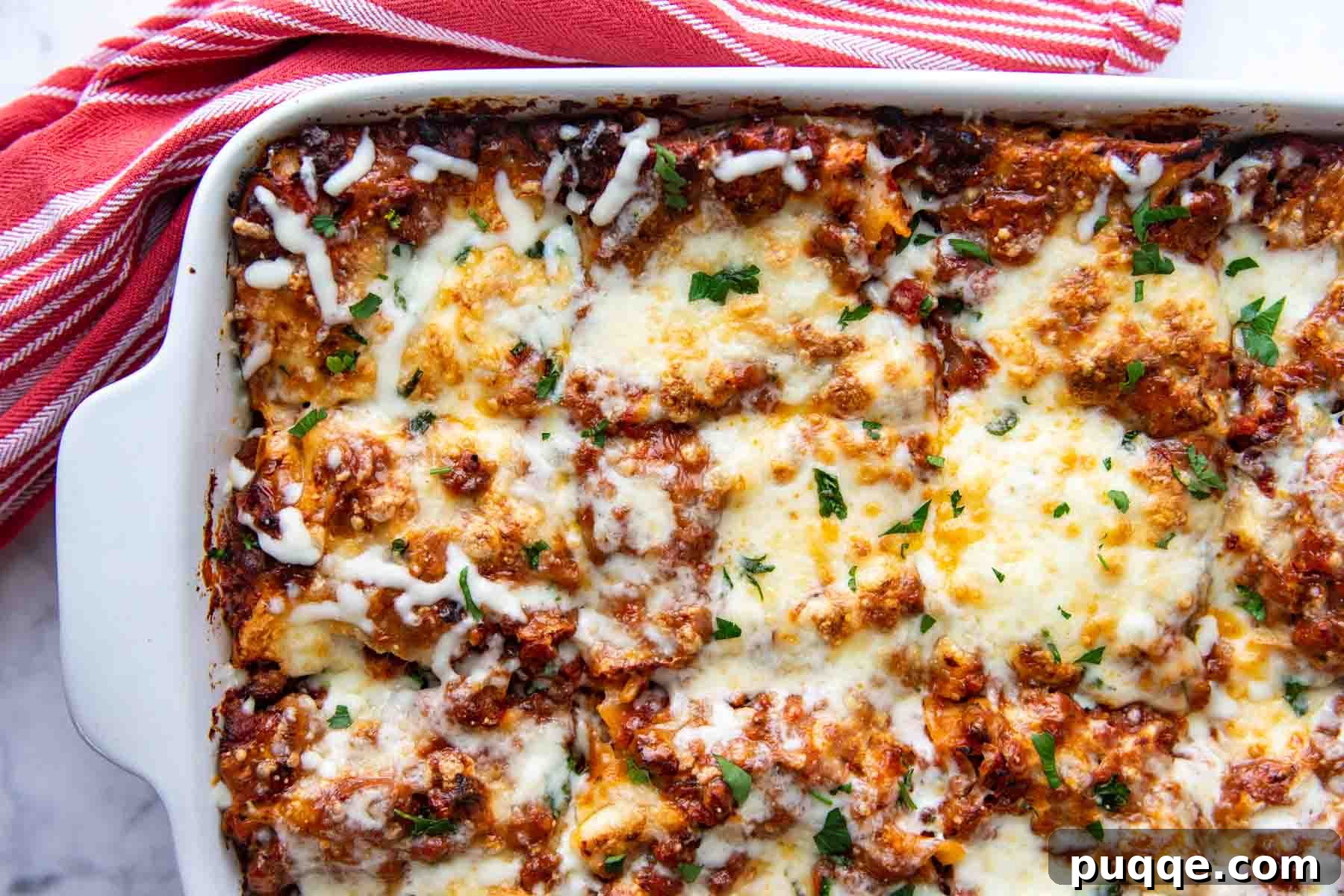 A close-up overhead shot of a corner of a baked lasagna dish, showing the rich layers and melted cheese.