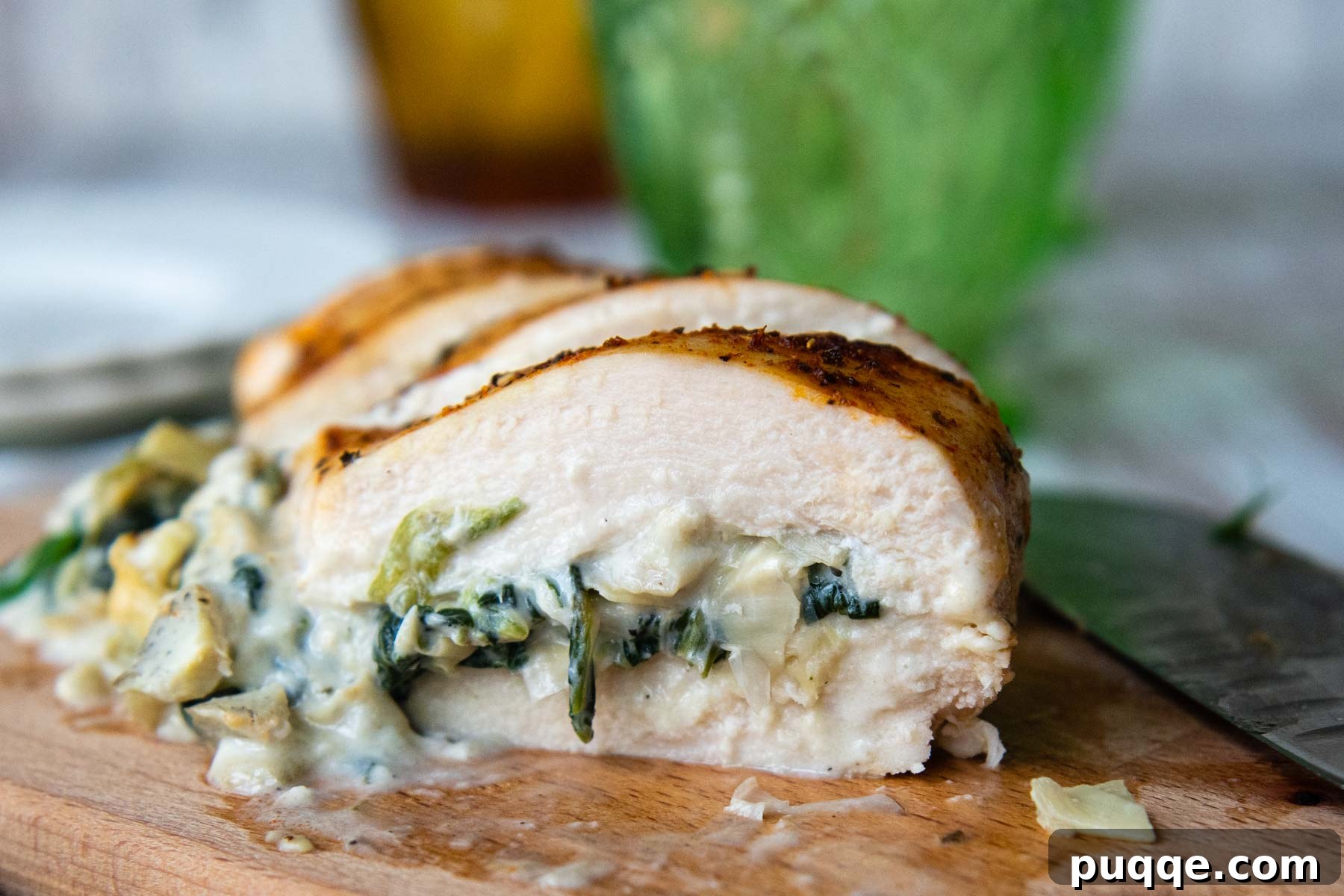 Close up of the inside of stuffed chicken breasts, showing the rich, creamy spinach artichoke filling.